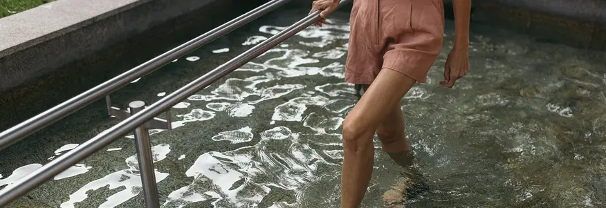 Frau hat ihre Füße im kalten Wasser beim Kneippen