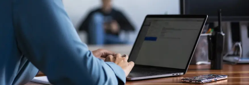 Ich sehe eine Frau mit blauer Bluse vor ihrem Laptop im Home-Office
